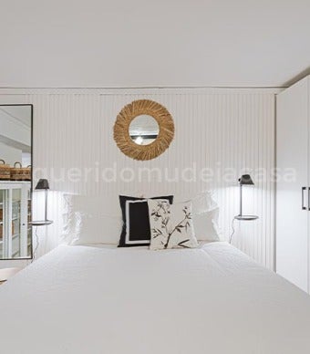 quarto de casal com ripas de madeira na cabeceira da cama e um espelho de ráfia